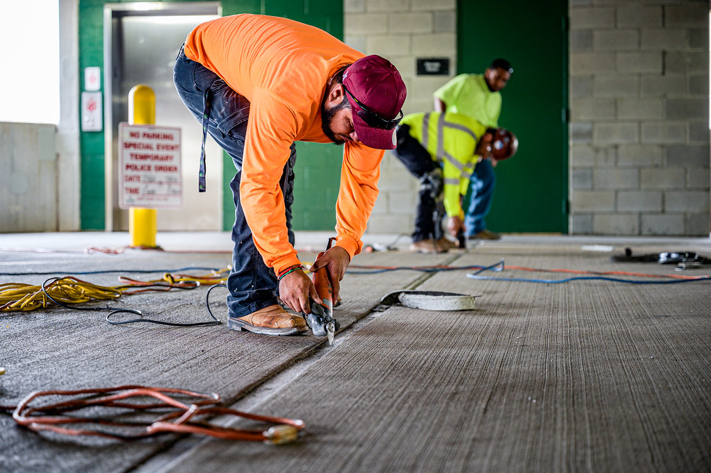 Crew removing a failed expansion-joint seal from a commercial concrete structure